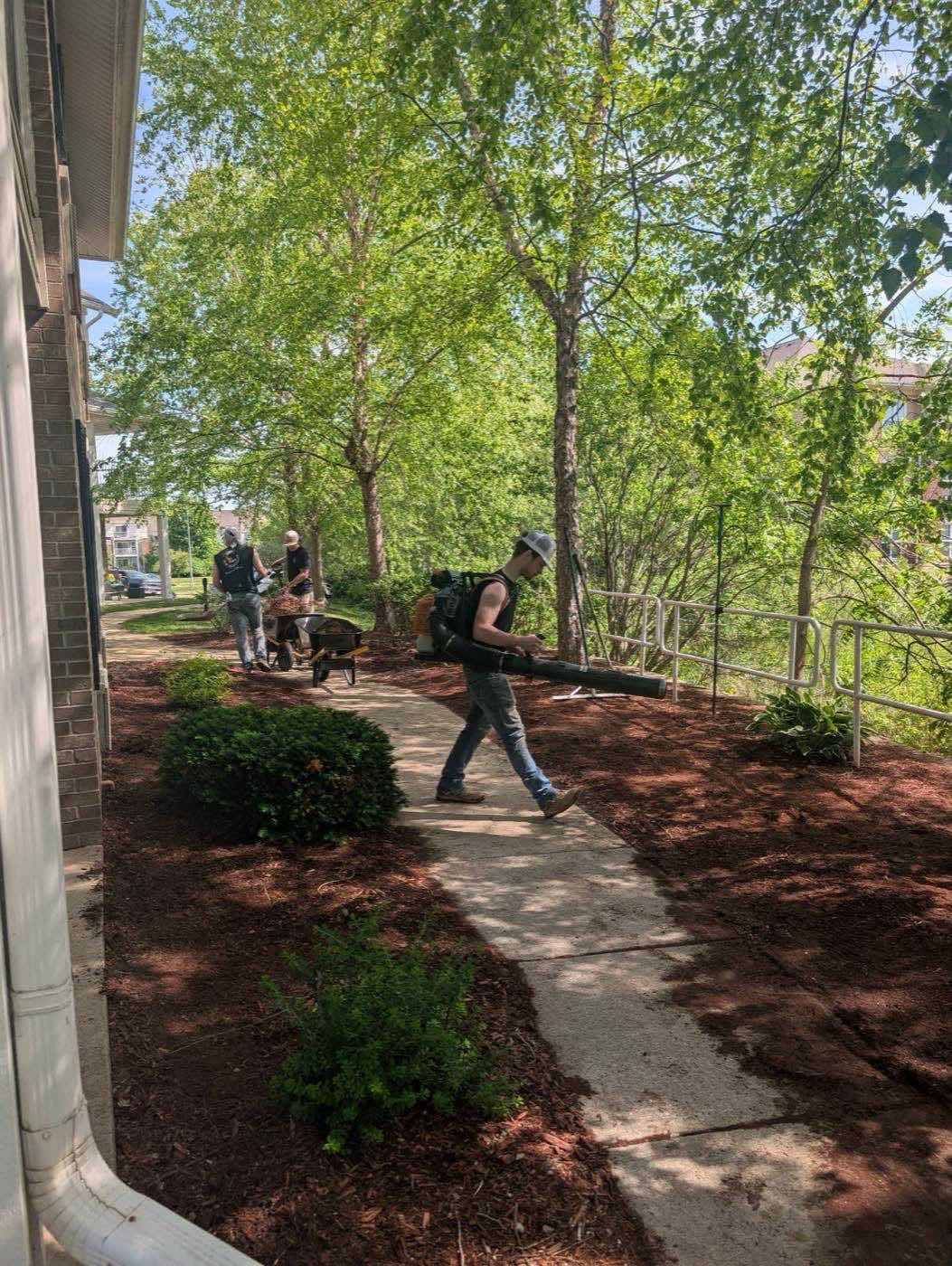 Crew member using a backpack blower to clear a walkway