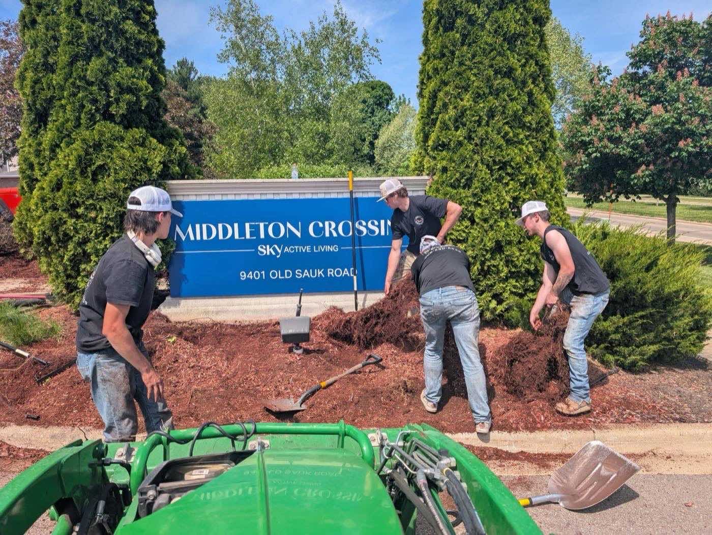Crew mulching beds around a commercial property sign