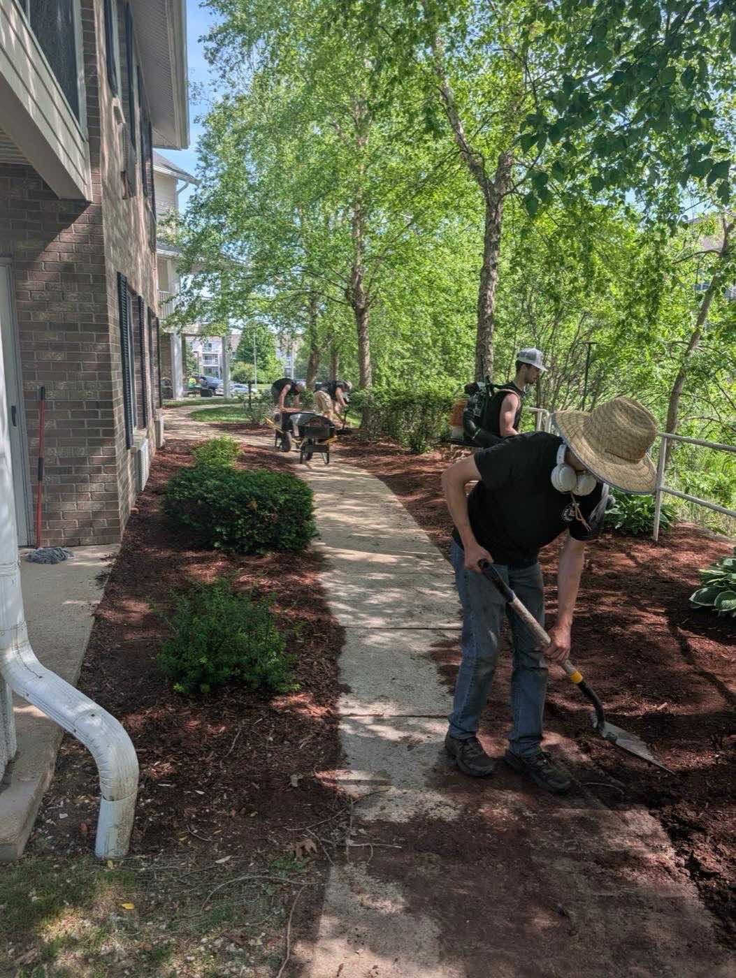 Crew mulching garden beds along a townhome walkway