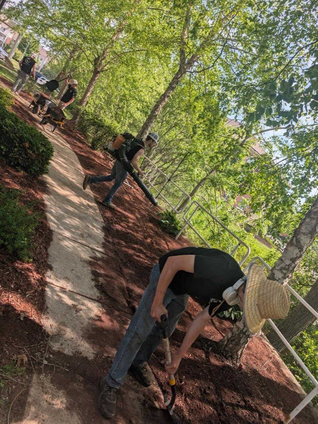 Crew member working a bed along a walkway lined with trees