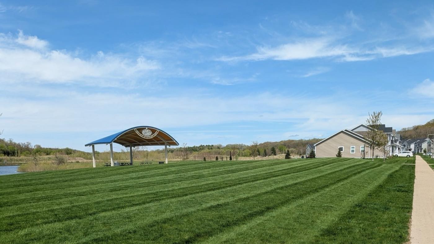 Freshly mowed lawn with wide stripes near a lakeside gazebo